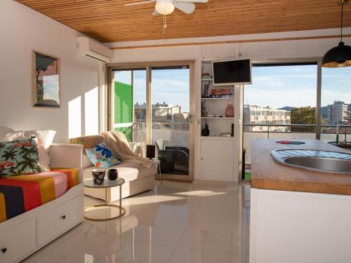 Il comprend un salon doté d'un canapé et une cuisine équipée d'un évier. dans l'établissement Studio avec terrasse, centre ville, climatisation, parking - FR-1-803-86, au Lavandou