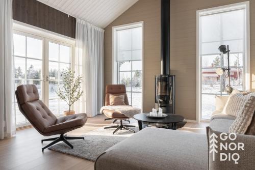 a living room with a couch and chairs and windows at The Red Fox Lodge in Tällberg
