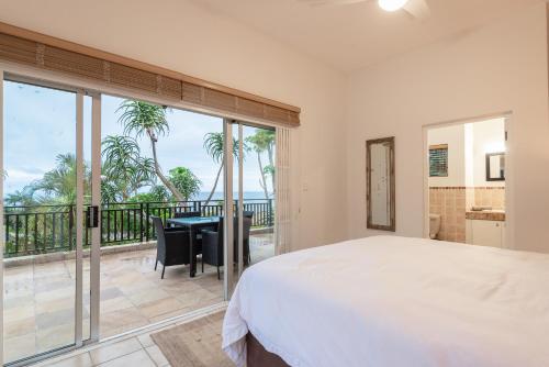a bedroom with a bed and a balcony with a table and chairs at The Hideaway at 88 in Ballito