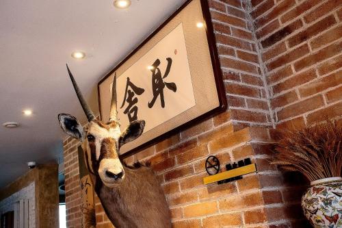 a statue of a deer hanging on a brick wall at Six-rafter Hall designer hot spring inn in Shangzhi