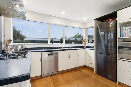 a kitchen with white cabinets and a stainless steel refrigerator at Christchurch Home away from home in Christchurch
