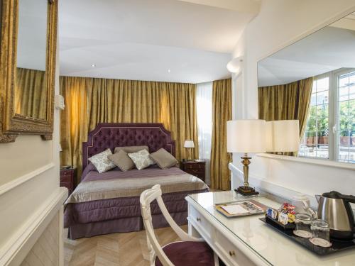 a bedroom with a bed and a desk and a mirror at The Britannia Hotel in Rome