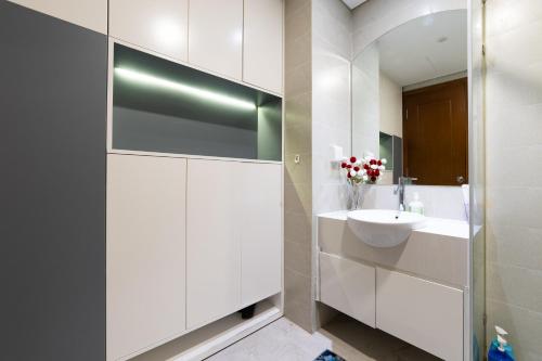 a white bathroom with a sink and a mirror at Vinhomes Central Park Apartment - Landmark Plus Luxury in Ho Chi Minh City