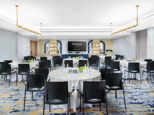 a conference room with tables and chairs and a screen at voco Jeddah Gate by IHG in Jeddah