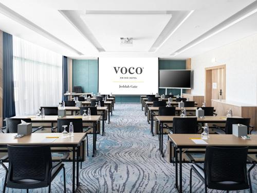 a classroom with tables and chairs and a screen at voco Jeddah Gate by IHG in Jeddah