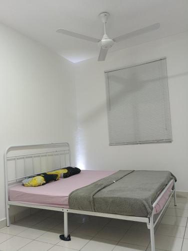 a bed in a white room with a ceiling fan at mazya homestay in Melaka