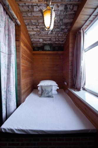 a small bed in a wooden room with a window at Six-rafter Hall designer hot spring inn in Shangzhi