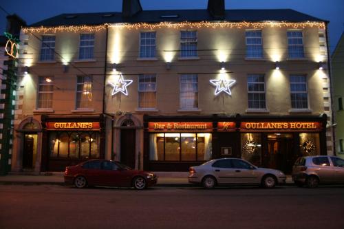 two cars parked in front of a building with christmas lights at Gullane's Hotel in Ballinasloe