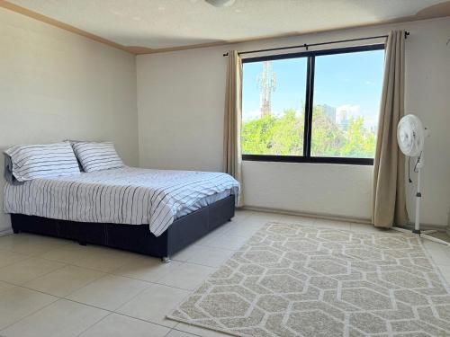 a bedroom with a bed and a large window at Departamento enteró en Mayorazgo in El Gallinero