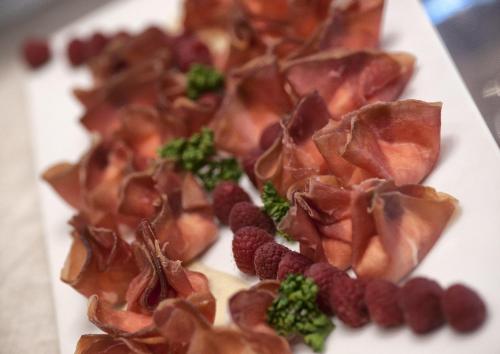 a plate of food with bacon broccoli and raspberries at Hotel Sporting in Rimini