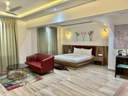 a hotel room with a bed and a red chair at The Grand Imperial in Pune