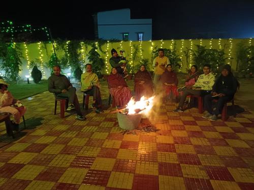 a group of people sitting around a fire at Swet Palash Resort in Purulia