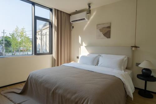 a bedroom with a bed with a large window at Eden Yard Boutique Hotel and Experiences in Xianghu