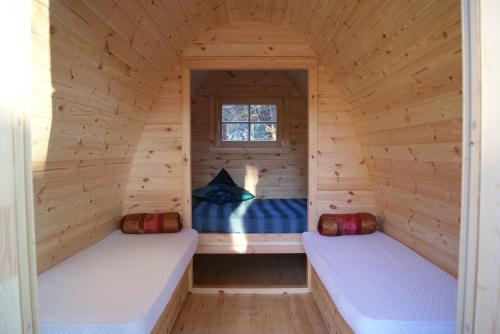two beds in a wooden cabin with a window at Camping Dolce Sole in Marina di Massa