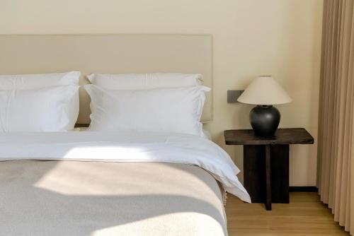a bed with white sheets and a table with a lamp at Eden Yard Boutique Hotel and Experiences in Xianghu