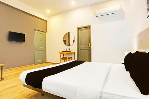 a bedroom with a large white bed and a mirror at Super Townhouse Vijay Khand Gomti Nagar in Lucknow