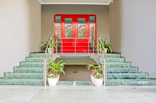 a staircase with a red door and potted plants at Super Townhouse Vijay Khand Gomti Nagar in Lucknow