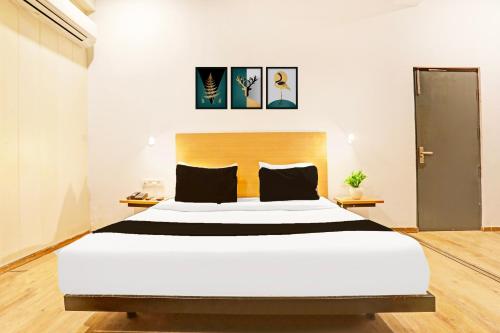 a bedroom with a large white bed with black pillows at Super Townhouse Vijay Khand Gomti Nagar in Lucknow