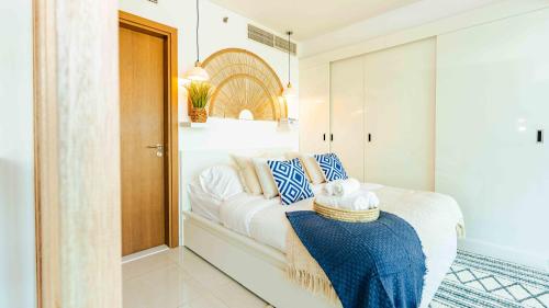 a bedroom with a white bed with blue and white pillows at Studio In Al Hadeel Hosted By Voyage in Abu Dhabi