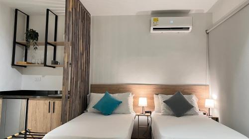 two beds in a small room with white and blue pillows at HOTEL 9.5 SAN FERNANDO in Cali