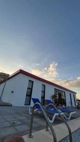 a white building with blue chairs in front of it at مزرعة-جوري--Jory-Farmhouse in Hatta