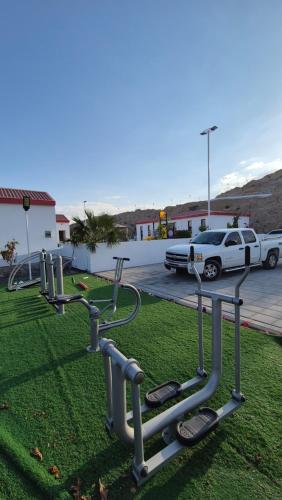 a row of gym equipment on the grass in a parking lot at مزرعة-جوري--Jory-Farmhouse in Hatta