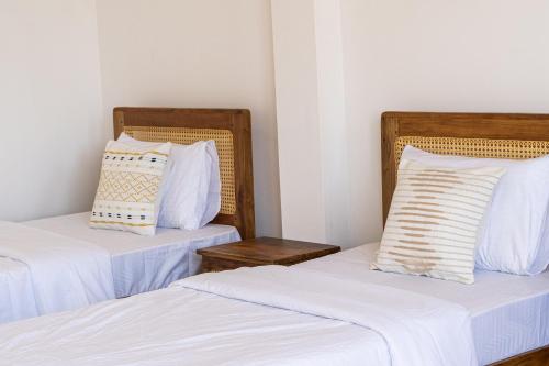 two beds with white sheets and pillows in a room at Sansun Guesthouse in Mirissa