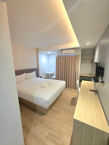 a bedroom with a large white bed and a table at Prom Hotel in Bangkok