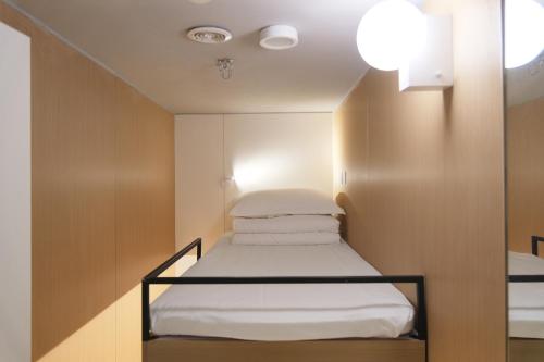 a small room with a bed with white sheets at wohkoon Youth Hostel Sanlitun Taikoo Li Branch in Beijing