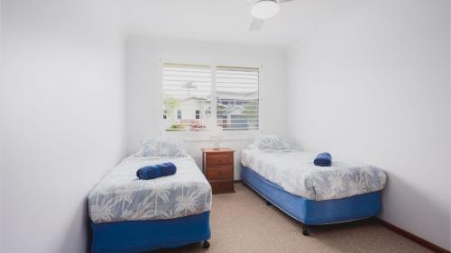 two twin beds in a room with a window at Roby's Retreat in Sawtell