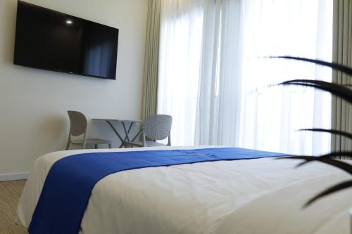 a bedroom with a bed and a flat screen tv at Lá Riverside Boutique Hotel in Mỹ Phước