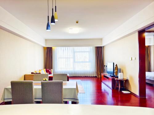 a hotel room with a dining table and a living room at Tianjin Crown International Apartment in Tianjin