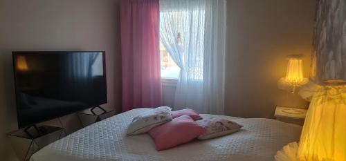 a bedroom with a bed with pillows and a television at Viihtyisä saunallinen rivitalokolmio in Alatornio