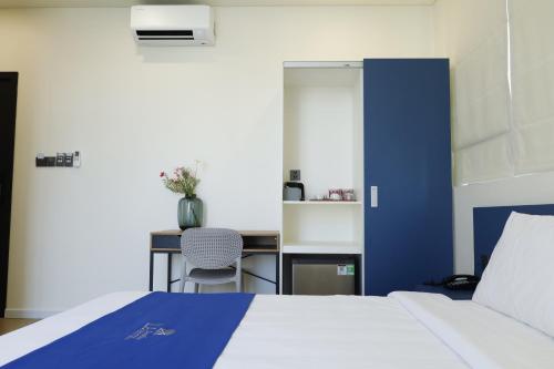 a bedroom with a blue and white bed and a desk at Lá Riverside Boutique Hotel in Mỹ Phước