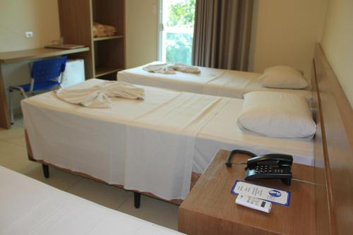 une chambre d'hôtel avec un lit, une table et un téléphone dans l'établissement Hotel do Farol, à Cubatão