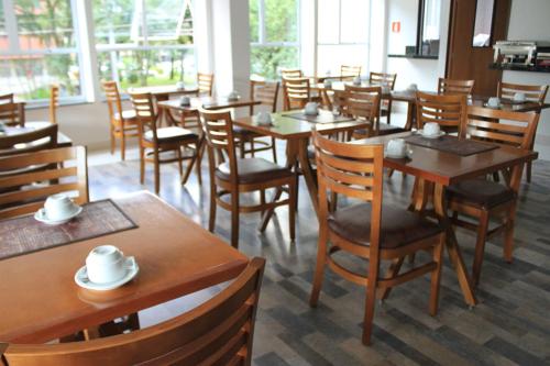 une salle à manger avec des tables et des chaises en bois dans l'établissement Hotel do Farol, à Cubatão