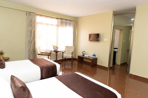 a hotel room with two beds and a window at Maxland Hotel in Nairobi