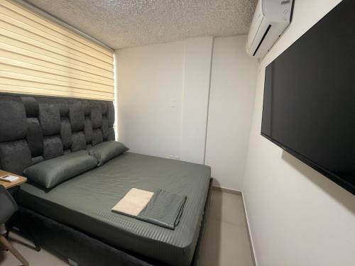 a small room with a couch and a television at Hermosa habitación a una cuadra del Ventura plaza 2 in Cúcuta