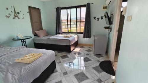 a room with two beds and a table and a window at โซพราว เขาค้อ So Proud Khaokho in Khao Kho