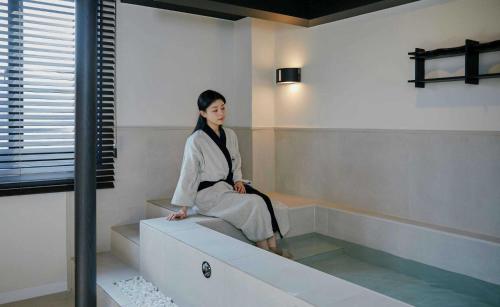 a woman sitting on a ledge in a room at Aank Hotel and Spa Jongno Unni in Seoul