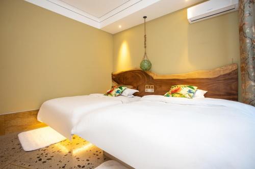 two beds in a room with white sheets at Six-rafter Hall designer hot spring inn in Shangzhi
