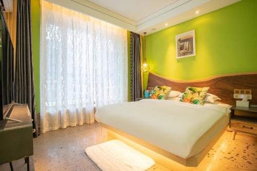 a bedroom with a large bed with a green wall at Six-rafter Hall designer hot spring inn in Shangzhi