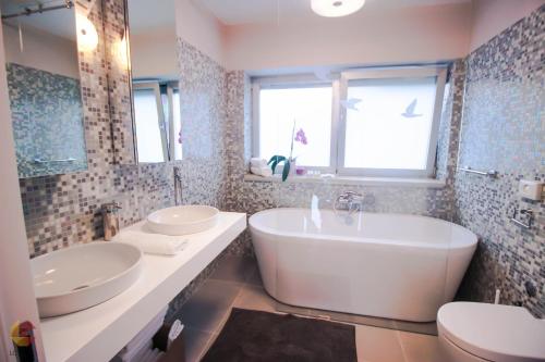 a bathroom with two sinks and a tub and a toilet at Villa Terra Rossa Borik in Rovinj