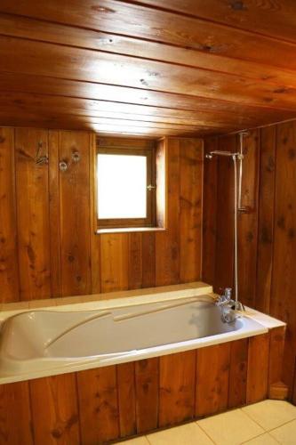 Cette chambre dispose de murs en bois et d'une grande baignoire. dans l'établissement Maison de montagne chez Baptiste, à Ascou