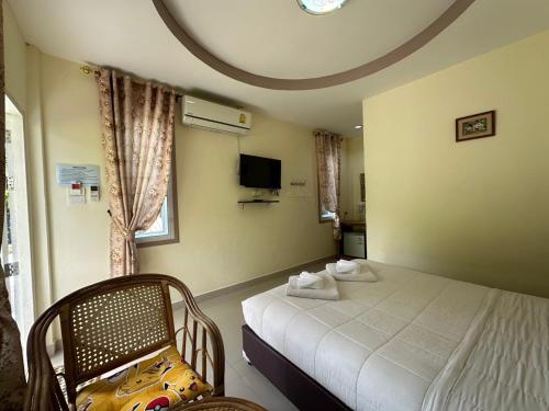 a bedroom with a bed and a chair and a tv at ชอว์ งาทอง รีสอร์ต Chor Ngar Thong Erawan Kanchanaburi in Kanchanaburi