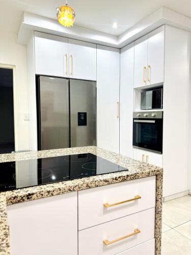 a kitchen with white cabinets and black appliances at Zaidi Luxury Home in Secunda