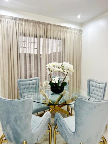 a dining room with a glass table and blue chairs at Zaidi Luxury Home in Secunda