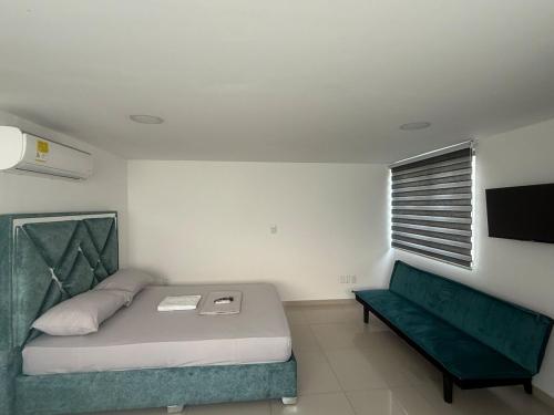 a bedroom with a bed and a green couch at Hermosa habitación a una cuadra del Ventura plaza 5 in Cúcuta