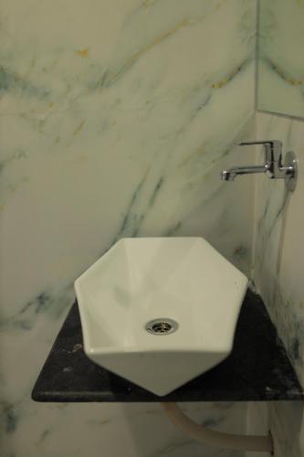 a white sink in a bathroom with a marble wall at Hotel Maruti R in Ahmedabad