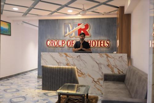 a man standing behind a counter in a group of hotels at Hotel Maruti R in Ahmedabad